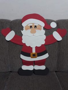 a cardboard santa clause sitting on top of a couch with his arms outstretched in the air