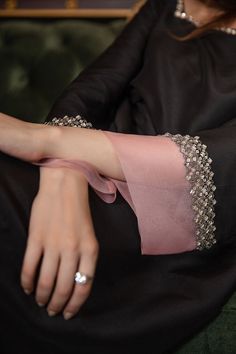 a woman sitting on top of a green couch wearing a black dress and diamond jewelry