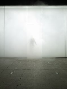 a man standing in front of a white wall with fog coming from the top and bottom