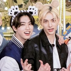 three young men standing next to each other with mickey ears on their head and one wearing a black jacket