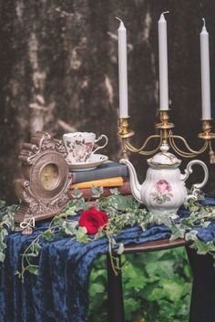 a table topped with books and candles on top of a blue cloth covered tablecloth