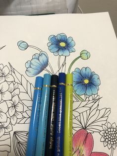 four crayons sitting on top of a coloring book with flowers in the background