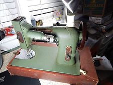 an old green sewing machine sitting on top of a wooden table next to a window