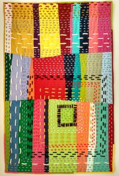 a multicolored quilt hanging on the wall