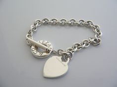 Overview:Offered for sale is a wonderful and gorgeous Tiffany & Co. Sterling Silver Heart Toggle bracelet. Definitely a Tiffany piece that you will get your money's value for. It works perfectly with pretty much any attire your put on, AND is a great statement piece. The chain for this specific bracelet very substantial, and the pretty Tiffany heart just goes perfectly with it. It is the perfect bracelet that fits a lifestyle on the go -- can be worn to pretty much any occasion! It is simple Toggle Bracelet, Gift Pouch, Bracelet Bangle, Sterling Silver Heart, Tiffany Heart, The Pretty, Heart Charm Bracelet, Silver Heart, Tiffany & Co.