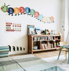 there is a bookcase in the room with many books on it and an area rug for children to play