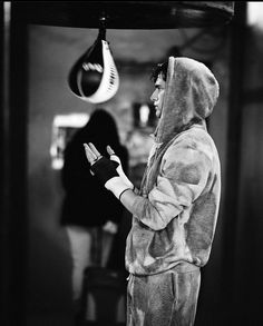 a man in a hoodie is holding his hand out to someone wearing a boxing glove