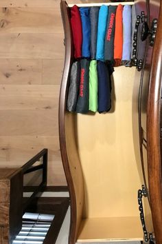 an open wooden closet with several different colored umbrellas hanging from it's sides