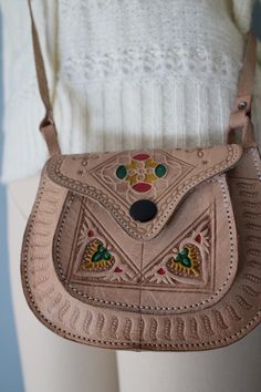 Vintage cute little Ethnic handmade saddle bag in sepia beige color. Colorful ornament front. Flap cover with push pin. Adjustable shoulder strap with buckle. Measurements: 6" x 5", 50" handle Condition: excellent! Traditional Leather Saddle Bag, Traditional Hand Tooled Saddle Bag, Traditional Hand Tooled Shoulder Bag As A Gift, Traditional Brown Crossbody Satchel, Traditional Crossbody Saddle Bag, Traditional Brown Leather Saddle Bag, Traditional Brown Satchel Saddle Bag, Traditional Satchel Saddle Bag For Daily Use, Bohemian Brown Satchel As Gift