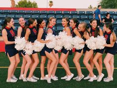 a group of cheerleaders standing on top of a field