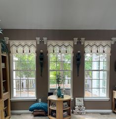 a living room filled with furniture and windows covered in shades of brown, blue and white