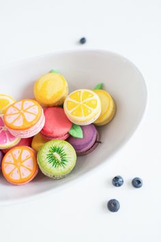 a white bowl filled with colorfully decorated macaroons