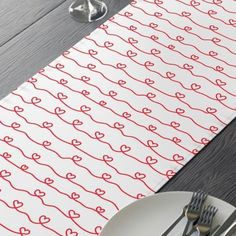 a place mat with red hearts on it next to silverware and utensils