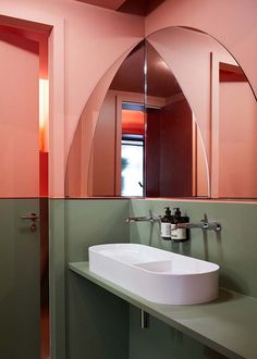 a bathroom sink sitting under a mirror in front of a pink and green counter top