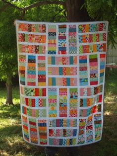 a large quilt is hanging on the side of a tree