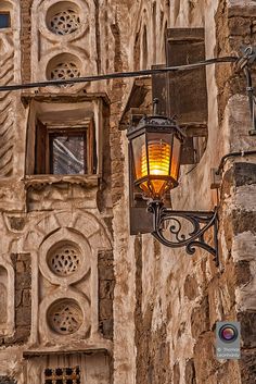 a street light hanging from the side of a building next to a wall with holes in it