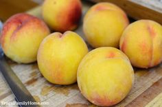 four peaches sitting on top of a cutting board with a knife next to them