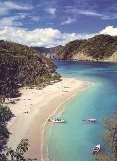 two boats are on the beach in clear blue water