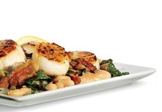 scallops, beans and greens on a white plate