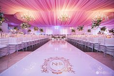 an indoor wedding venue with pink draping and chandeliers on the ceiling