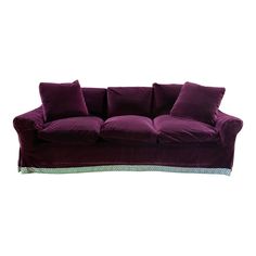 a purple velvet couch with pillows on it's arms and back cushions, sitting in front of a white background