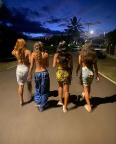 three girls walking down the street at night with their backs turned to the same direction