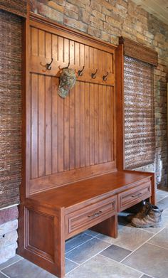 a wooden bench sitting in front of a brick wall with hooks on it's sides