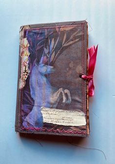 an altered book with a red ribbon tied to it's side on a blue surface