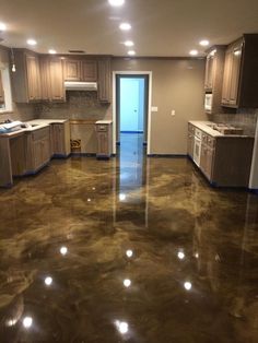 an empty kitchen and living room with shiny metallic flooring in the middle of it