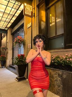 a woman in a red dress is posing for the camera with her hands on her face