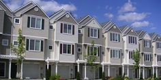 a row of houses with white trim and windows on each side, in front of a blue sky