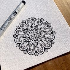 a pen is sitting on top of a piece of paper with an intricately designed design