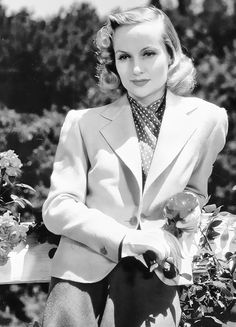 black and white photograph of a woman sitting on a bench with flowers in her lap