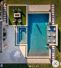 an aerial view of a pool and patio with umbrellas in the grass next to it