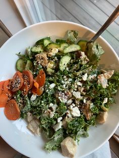 a white bowl filled with salad and sliced veggies on top of a table