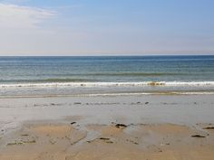 an empty beach with the ocean in the background