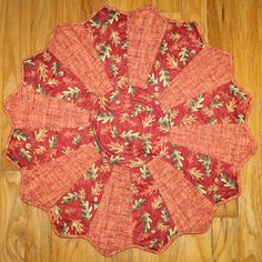 a red and green table cloth with leaves on it sitting on top of a wooden floor