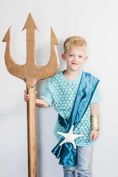 a young boy is standing next to a giant wooden anchor and holding it in his hand