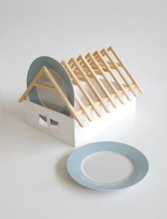 a white plate with a blue rim next to a small house shaped dish rack on a white surface