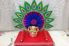 an elephant figurine sitting on top of a red box next to a peacock fan