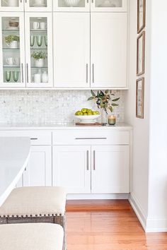 a kitchen with white cabinets and counter tops, along with a bowl of fruit on the counter