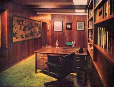 an old photo of a home office with wood paneling and green carpet on the floor