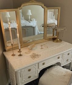 a white vanity with two mirrors and a stool