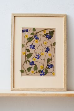 a white frame with blue and yellow flowers on it next to a wall mounted object