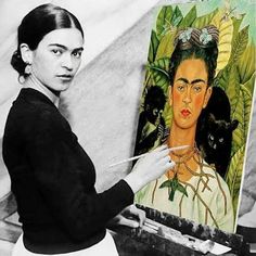 a woman holding a brush in front of an easel with a painting on it