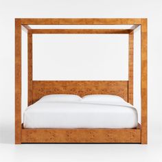 a wooden bed with white sheets and pillows