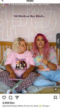 two women sitting on top of a bed next to each other in front of a pink wall