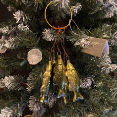 three gold fish ornaments hanging from a christmas tree