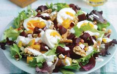 a salad on a plate topped with eggs and other toppings, sitting on a checkered table cloth