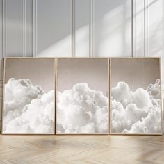 three frames with white clouds in them on a wooden floor next to a wall and window